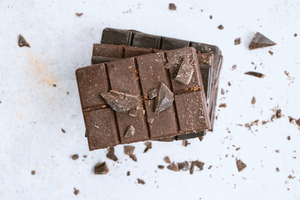 two bars of milk chocolate lay flat, one on top of the other with smashed pieces around them