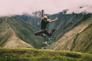 Woman jumping on top of a mountain